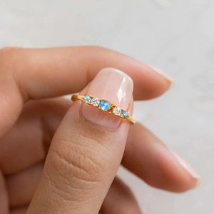 Macro view of slender gold S925 silver ring with five symmetrical blue and white stones