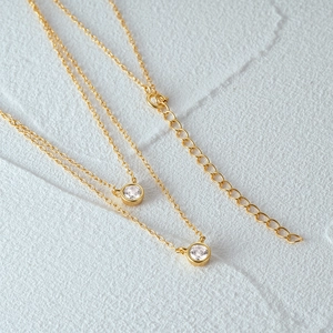 Macro detail of gold S925 silver double layered necklace with sparkling zircon pendants