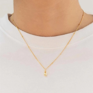 Detailansicht eines 18K Gold-Wassertropfenanhängers an einer Perlenkette auf weißem Hemd