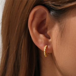Close-up of a gold-plated sterling silver hoop earring with small pavé-set zircons on ear