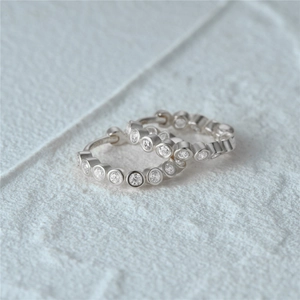 Macro shot of 925 silver hoop earrings with bezel-set cubic zirconia on stone