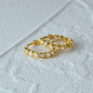 Macro detail of gold plated S925 silver hoop earrings with inset white zircon stones