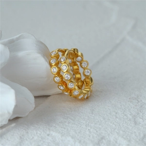 Detailed view of gold hoop earrings with white micro-pave crystals on stone background