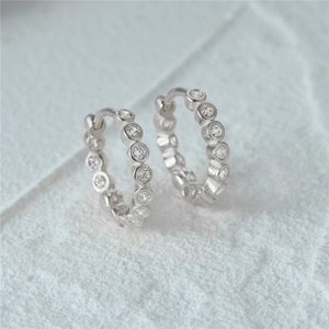 Macro shot of 925 silver hoop earrings with a single row of sparkling round-cut crystals