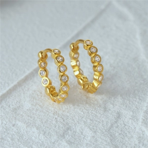 Detailed macro shot of gold-plated hoop earrings featuring inlaid round cubic zirconia stones