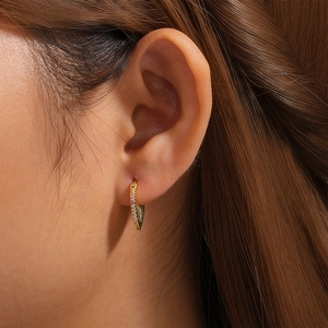 Close-up of golden fishtail earring with gradient purple stones worn by model
