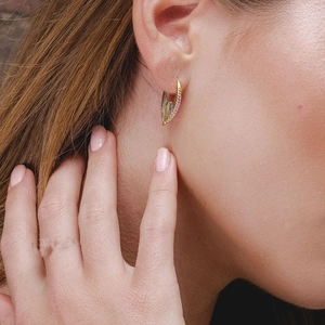 Detailed close-up of 925 silver fan-shaped earring with purple zircons on model ear