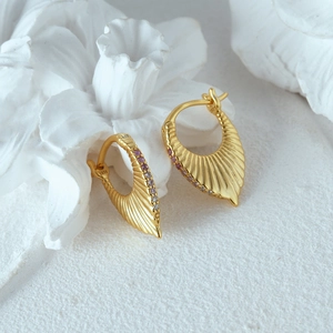 Macro shot of 925 silver gold-plated fan earrings with purple zircons on white stone