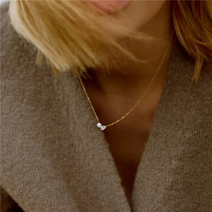 Detail of s925 silver necklace with round and pear cut zircons on gold chain