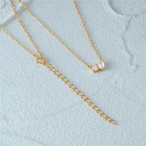 Detailed macro shot of a gold butterfly necklace with zircon stones on stone background