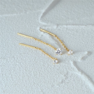Dettaglio del marchio 14K su orecchini con zirconi scintillanti e catene a pendente