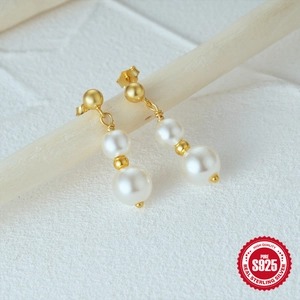 Elegant 925 sterling silver drop earrings with white pearls on a light wooden stand