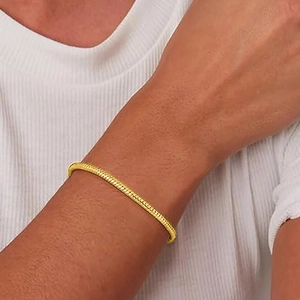 Detail of a minimalist gold-plated snake bone chain bracelet worn on a female wrist