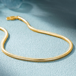 Close-up of flexible 18K gold plated silver snake chain with spiral texture on blue background