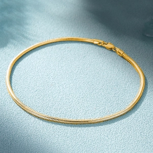 Detailed macro view of 18k gold plated flat snake chain bracelet with lobster clasp