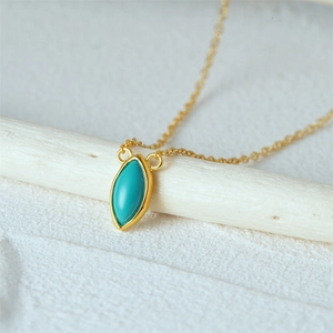Detailed close-up of a marquise turquoise pendant on a delicate gold-plated chain