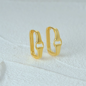 Macro shot of minimalist gold U-shaped earrings with a horseshoe link design on stone