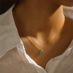 Close-up of minimalist gold necklace with marquise-cut turquoise pendant on model