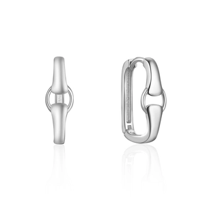 Macro view of silver U-shaped horsebit huggie earrings with a polished mirror finish