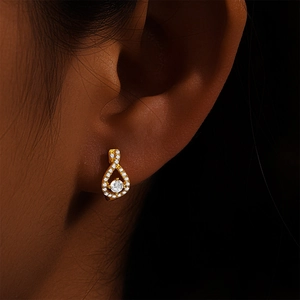 Detailed view of infinity drop earrings in gold with pavé stones on model