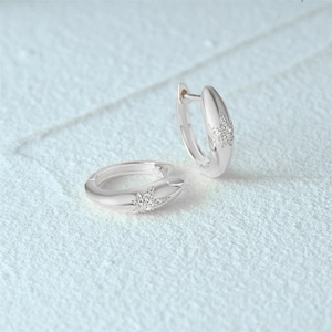 Macro shot of silver S925 hoop earrings featuring sparkling diamond cannabis leaf designs