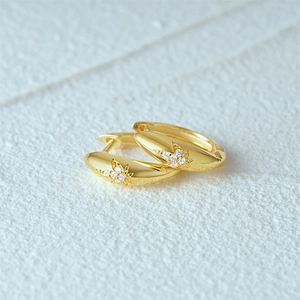 Detailed close-up of golden teardrop hoop earrings with star pattern and sparkling crystals