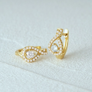 Macro shot of gold silver earrings with sparkling zircon drop shape and buckle closure