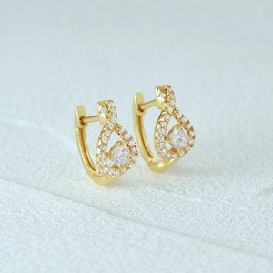 Macro shot of gold twist hoop earrings with sparkling white crystals and drop accents