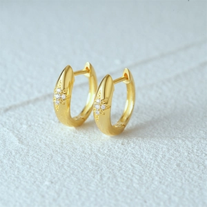 Macro view of gold hoop earrings with starburst engraving and micro-set cubic zirconia