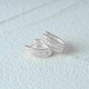 Detail of s925 silver huggie earrings with twisted rope texture and clear cubic zirconia