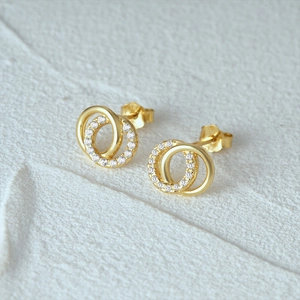 Détail macro de boucles d'oreilles doubles anneaux dorés avec pavage de zirconiums blancs