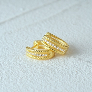 Macro shot of gold-plated hoop earrings with leaf twist texture and zircon inlay