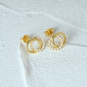 Vue macro de boucles d'oreilles double anneau en argent doré avec pavé de zircons brillants