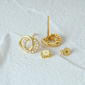 Gros plan du poinçon S925 sur des boucles d'oreilles double anneau en argent doré et zircons