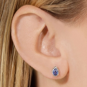 Detail van een peervormige blauwe edelsteen oorbel met een kralenrand van zilver