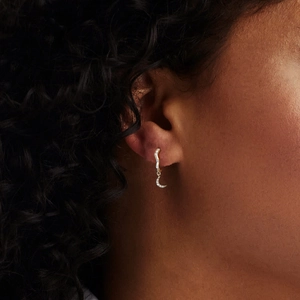 Close-up of gold moon earring with white zircon inlay worn by model in detail shot