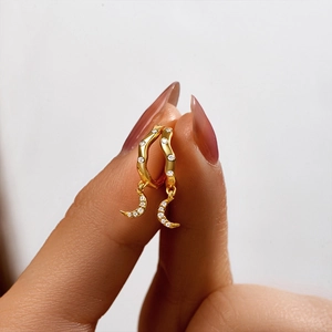 Macro shot of gold crescent moon drop earrings with sparkling wave-shaped zircon accents