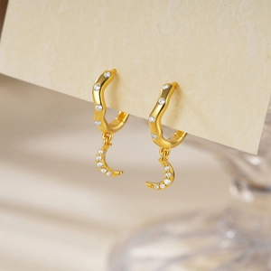 Detail view of gold moon-shaped drop earrings with pavé white zircon stones on display card