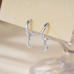 Macro shot of silver crescent moon drop earring with sparkling zircon inlays on wave band
