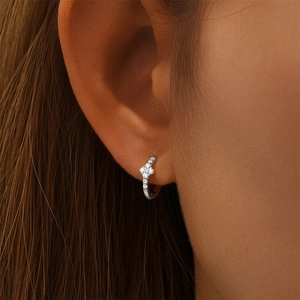 Close-up of S925 sterling silver hoop earrings with diamond clover charms on the ear