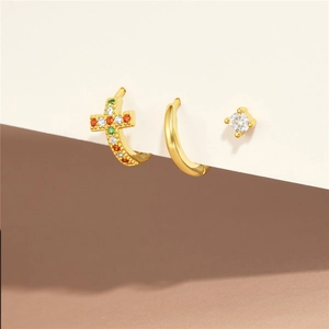 Dettaglio del set di orecchini in argento con croci di zirconi colorati su sfondo