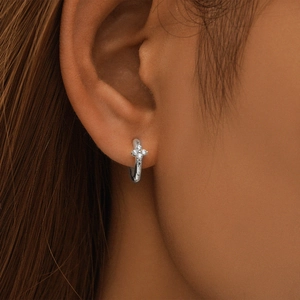 Detail of s925 silver hoop earring featuring four-petal flower zircon stones on ear