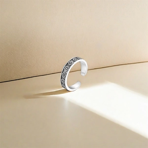 Macro detail of S925 sterling silver adjustable toe ring with embossed daisy floral pattern