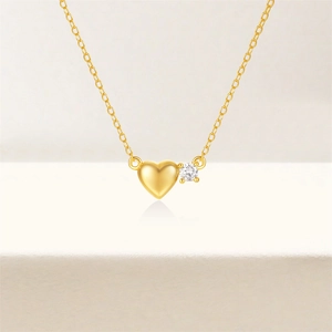 Detailaufnahme der herzförmigen Goldkette mit funkelndem Zirkon und eleganter Gliederkette