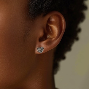 Macro shot of silver heart-shaped rose earrings with zircon inlay on female ear
