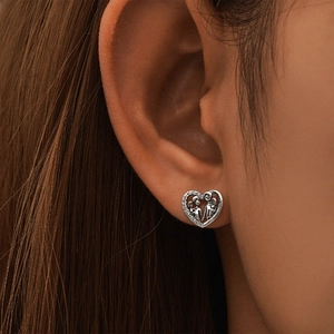 Detail of silver heart earring with cubic zirconia showing a family embrace motif