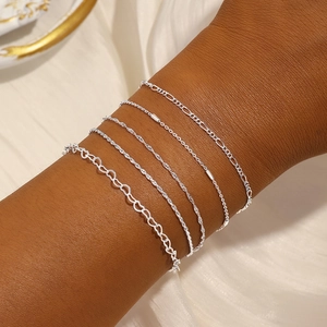 Detail eines 5-teiligen Silberarmband-Sets mit Herz- und Figaroketten am Handgelenk