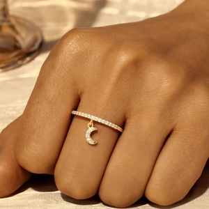 Detail of a gold S925 sterling silver ring with sparkling moon pendant on silken cloth