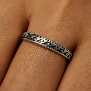 Macro shot of S925 silver wave ring with vintage oxidized finish and engraved details