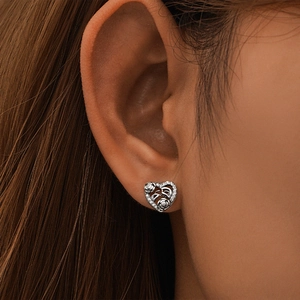 Detailed close-up of S925 silver heart stud earrings with hollow rose pattern on ear